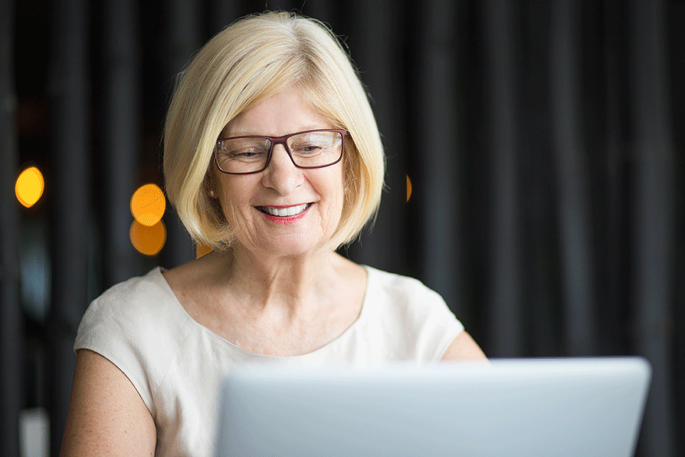 Blonde woman smiles while writing on her laptop